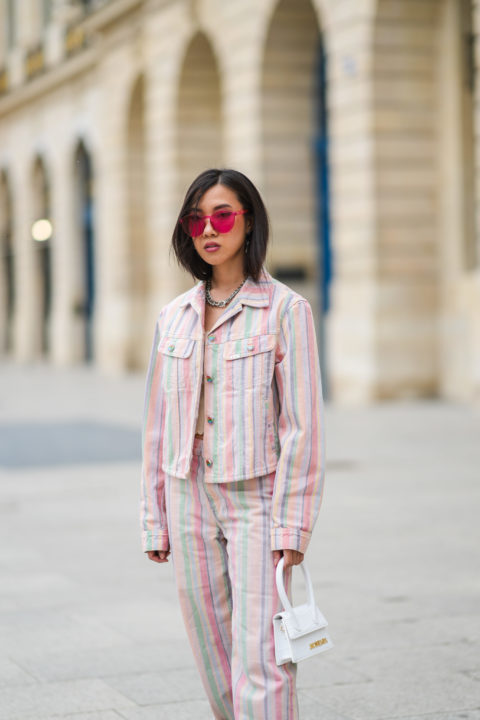 woman with tinted pink sunglasses and multicoloured jacket inspo for what to wear to pride 2022